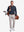 Front full body shot of model wearing navy solid stretch cotton pique long sleeve polo shirt while carrying a golf bag on back