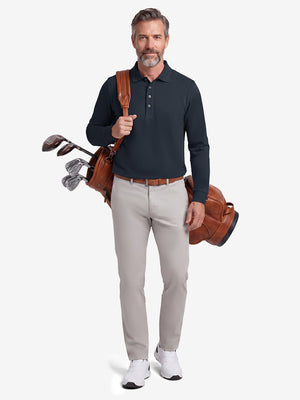 Front full body shot of model wearing dark navy solid stretch cotton pique long sleeve polo shirt while carrying a golf bag on back
