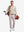 Front full body shot of model wearing light khaki solid stretch cotton pique long sleeve polo shirt while carrying a golf bag on back