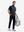 Front full body angled shot of model wearing black grey leaf2  full print quarter zip sleeveless vest pullover while carrying a  bag in one hand