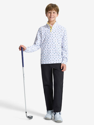 Front full body shot of model wearing  white golf  youth print midlayer Q-zip pullover sweatshirt with one hand resting on golf club