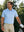 Front shot of model wearing light blue nylon blend casual jacquard polo shirt with hand resting on golf bag  on the golf course