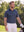 Front upper body angled shot of male model wearing dark blue premium ribbed collar print polo shirt, with one gloved hand resting on golf bag  on the golf course