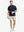 Detail shot with model holding a takeaway drink and sunglasses, featuring the NAVY polo’s side vent.