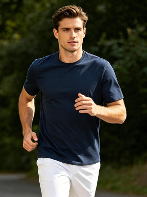 Front action shot of model wearing dark blue heather moisture wicking heather round neck athletic t-shirt while running